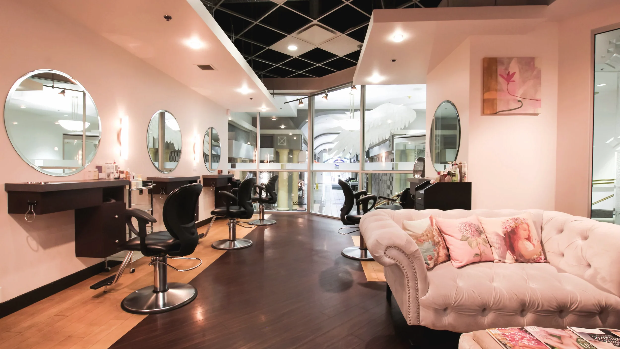 The salon at 736 View St, seen in one of its round mirrors: styling chairs, round mirrors and the tufted pink sofa